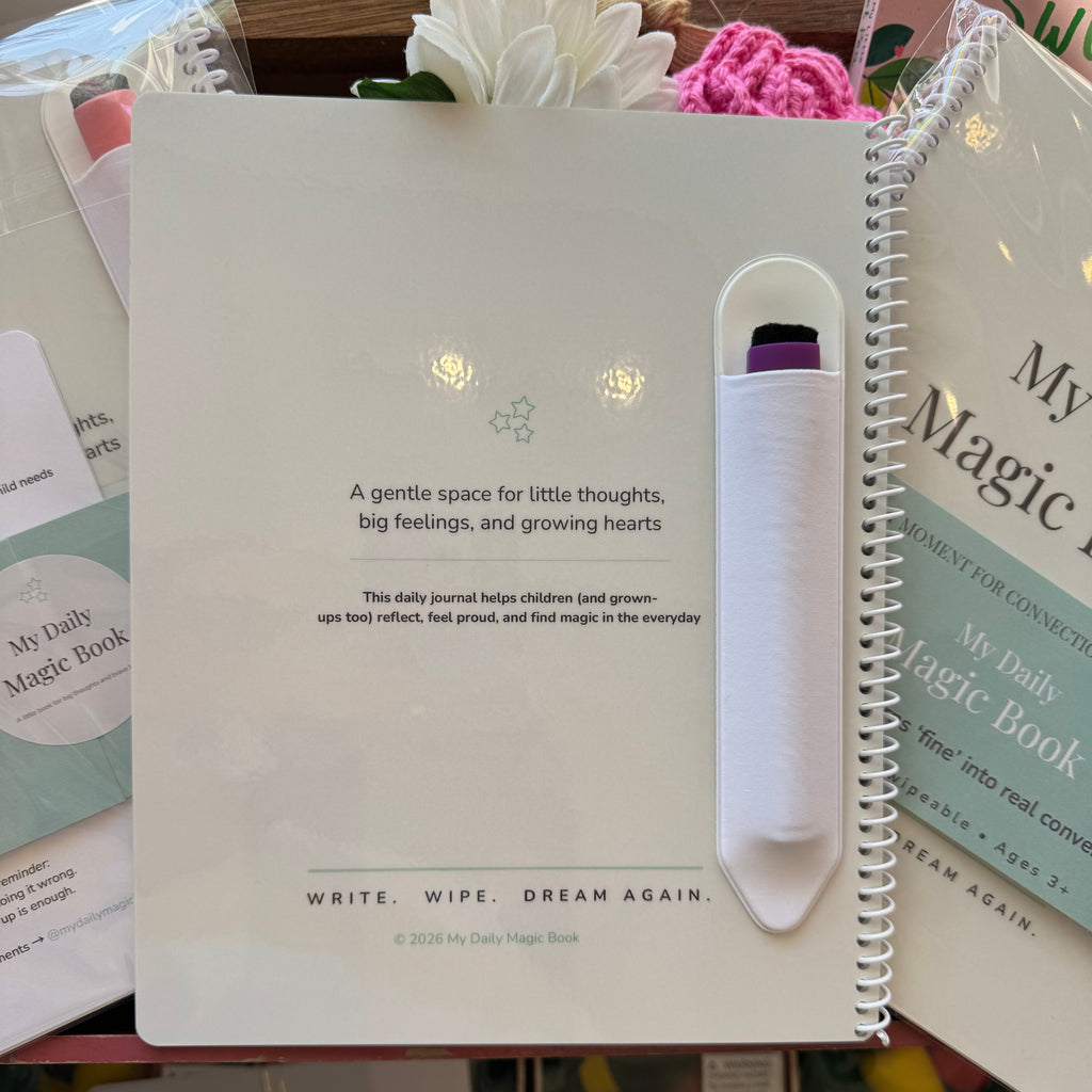 Notebook with a pen holder on top, surrounded by books and stationery items.