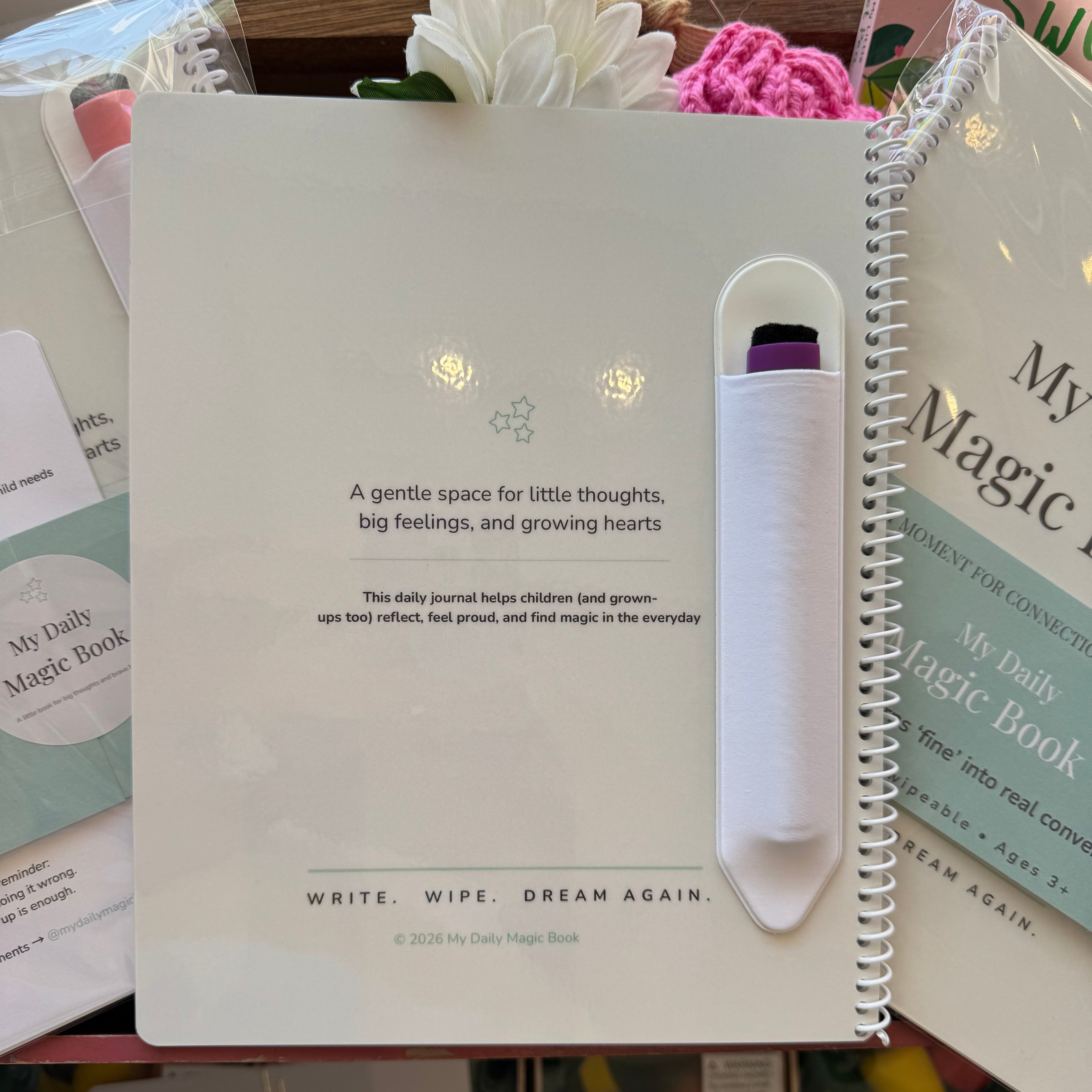 Notebook with a pen holder on top, surrounded by books and stationery items.
