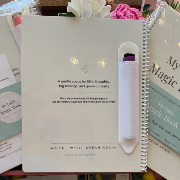 Notebook with a pen holder on top, surrounded by books and stationery items.