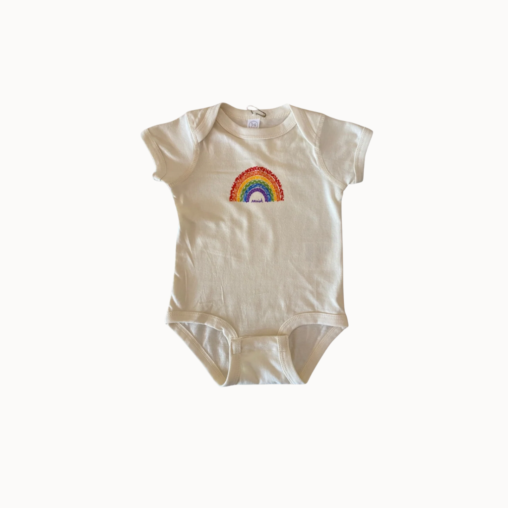 A short-sleeve baby bodysuit in cream-colored cotton, featuring a colorful embroidered rainbow with a white sun and blue sky motif on the chest, displayed against a plain white background.