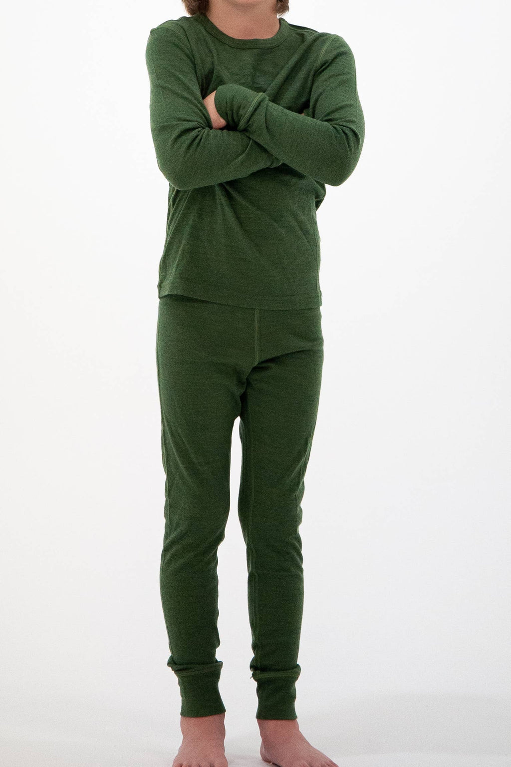 A child wearing a matching dark green long-sleeve top and pants set, standing with arms crossed against a plain white background.