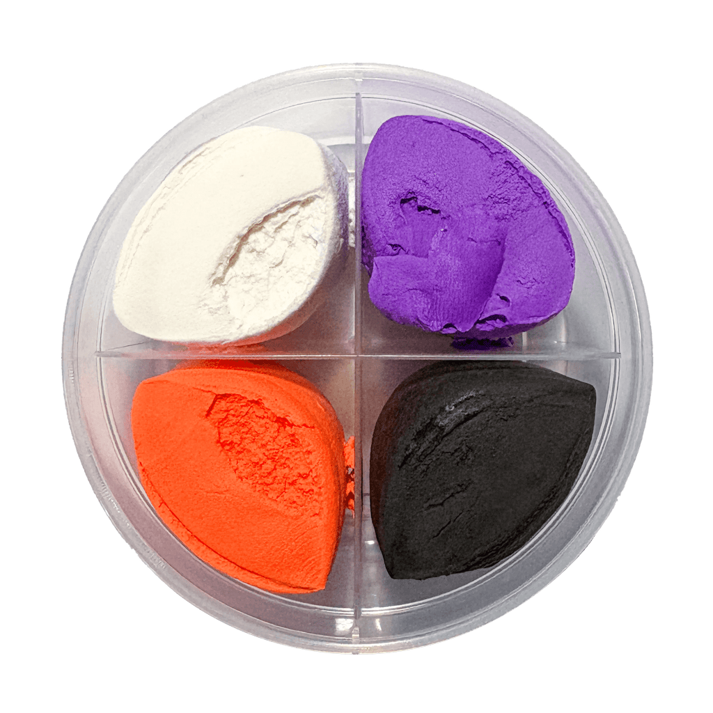 Four different colored clay pieces in a clear container on a white background