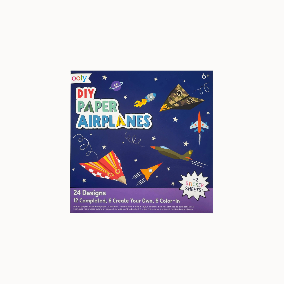 A DIY Paper Airplanes sticker kit box by Oooly, featuring a dark blue space-themed background with illustrated paper airplanes, rockets, stars, and planets. The packaging highlights 24 designs, 12 completed, and 6 color-in options.