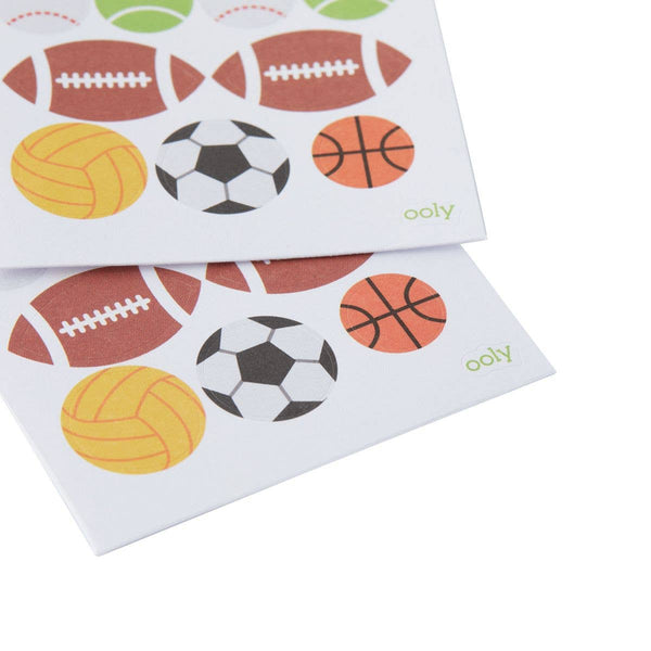 Two sheets of sports-themed stickers featuring footballs, soccer balls, and basketballs on a white background. Brand 'ooly' visible.