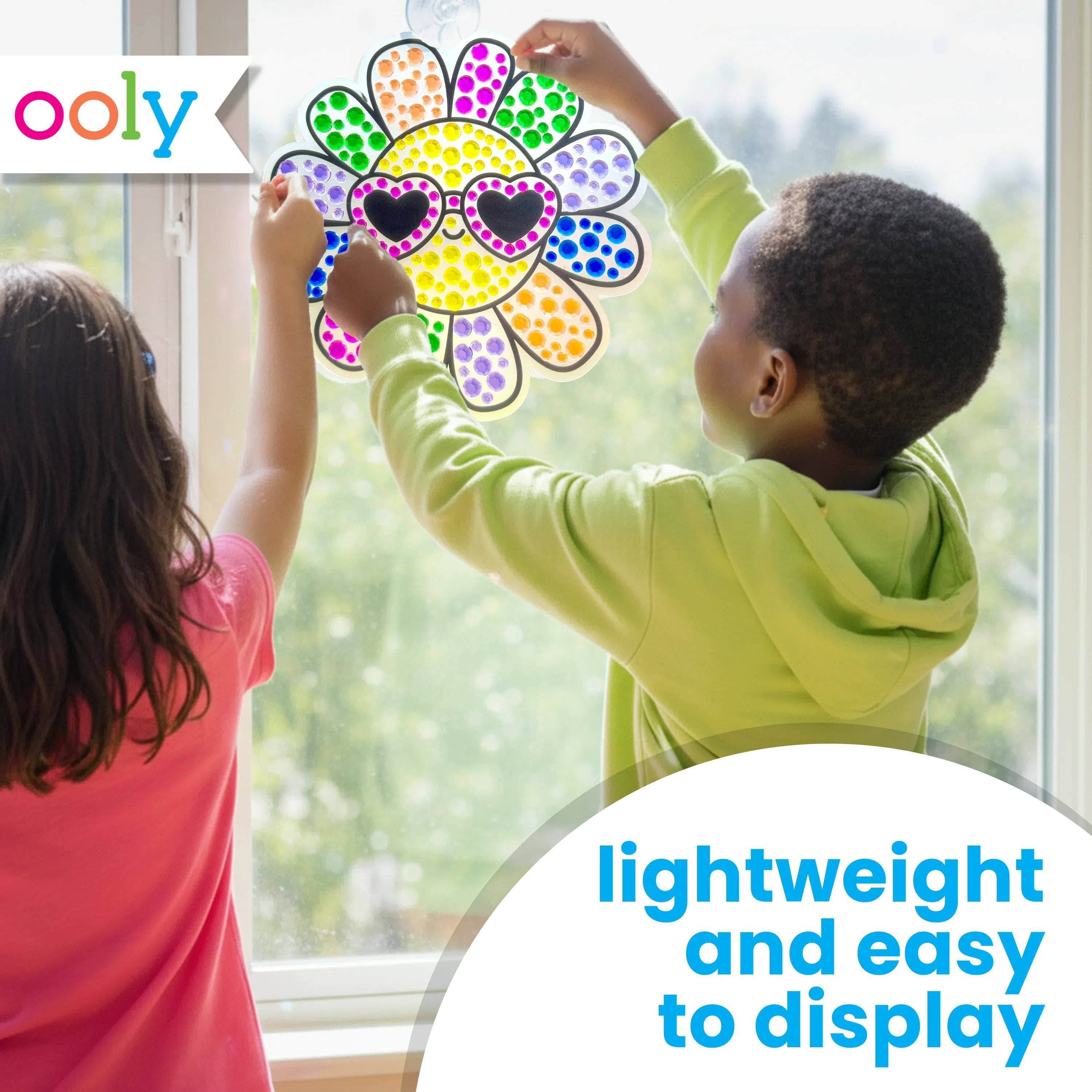 Two children decorating a window with colorful stickers, featuring the brand 'ooly'.