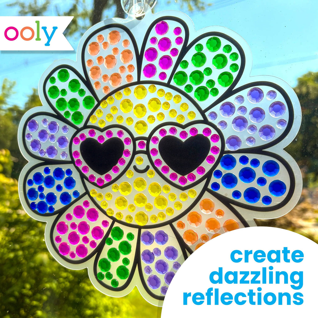 Colorful dot art sun catcher with heart-shaped eyes and 'ooly' branding.