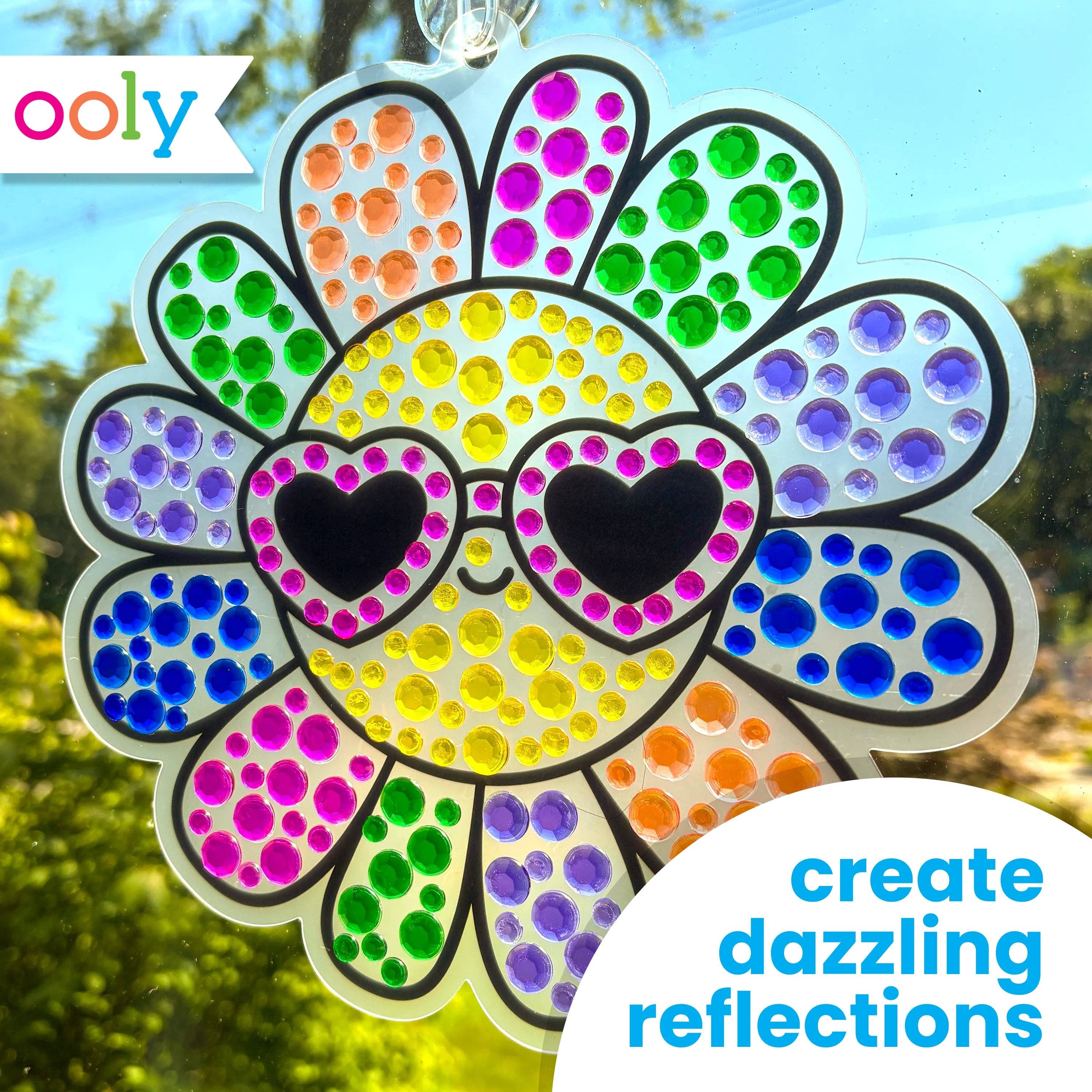 Colorful dot art sun catcher with heart-shaped eyes and 'ooly' branding.