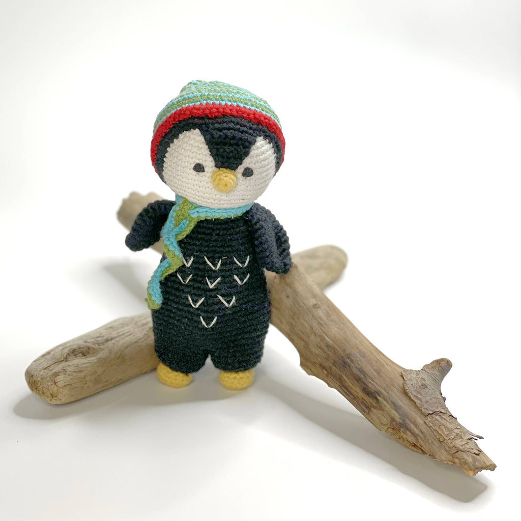 Knitted penguin toy with a colorful hat and scarf on a white background