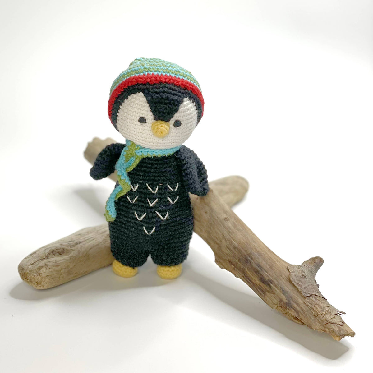 Knitted penguin toy with a colorful hat and scarf on a white background