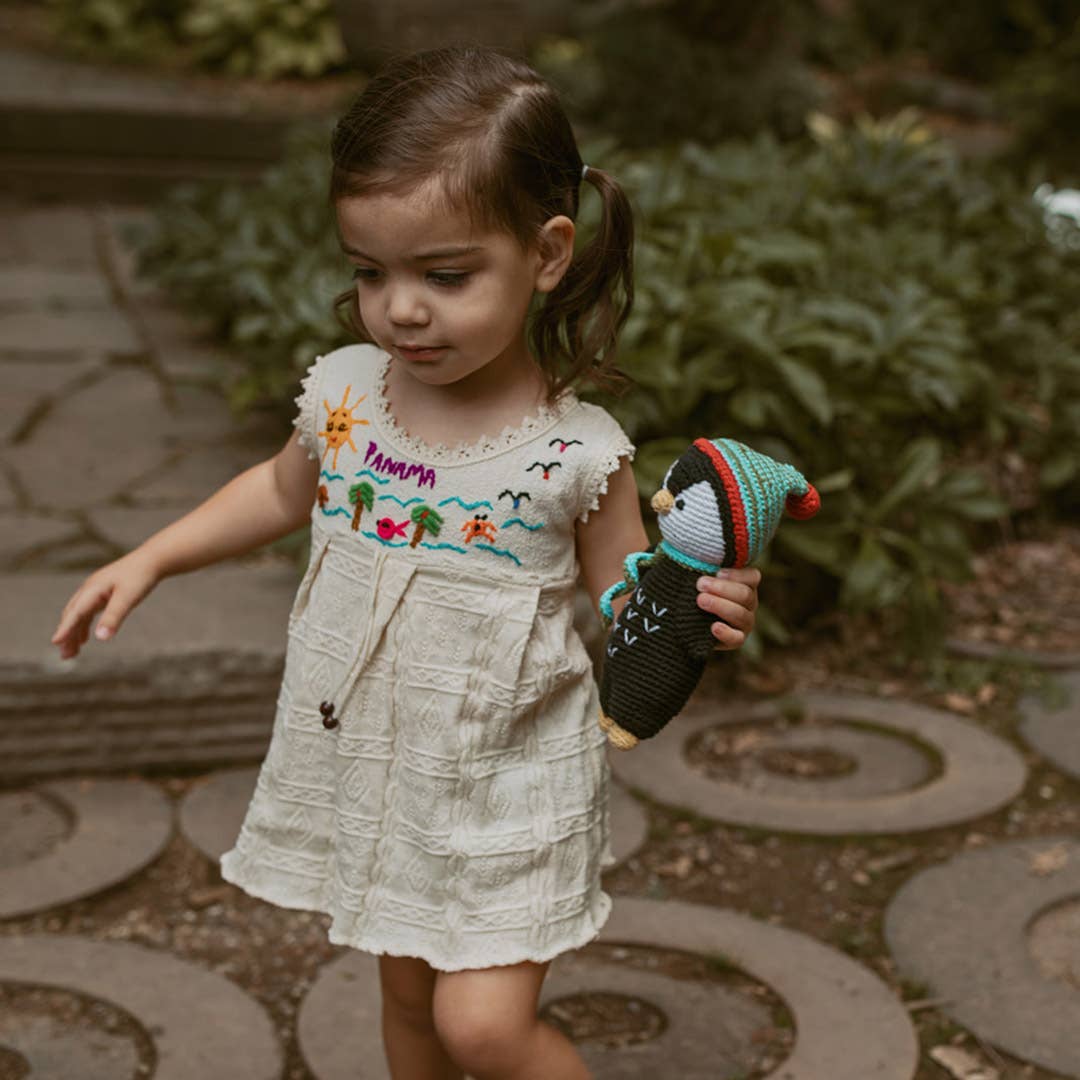 Young girl in a white dress with embroidery holding a toy in an outdoor setting
