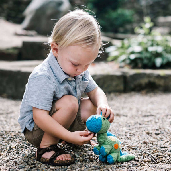Child playing with a toy dinosaur outdoors