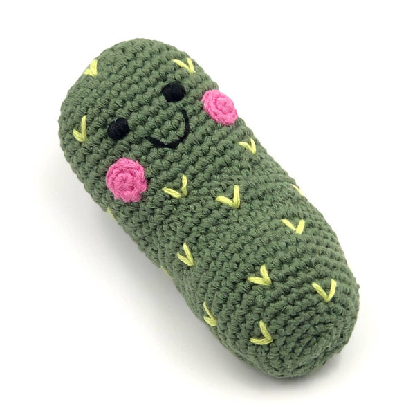 Green crocheted pickle-shaped toy with pink flowers and yellow leaves on a white background