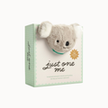 A boxed plush koala toy with the title 'just one' on the front, shown on a clean white background. The package is pale mint green with a grid pattern, and the koala is light gray with white ear flaps and a small teal collar.
