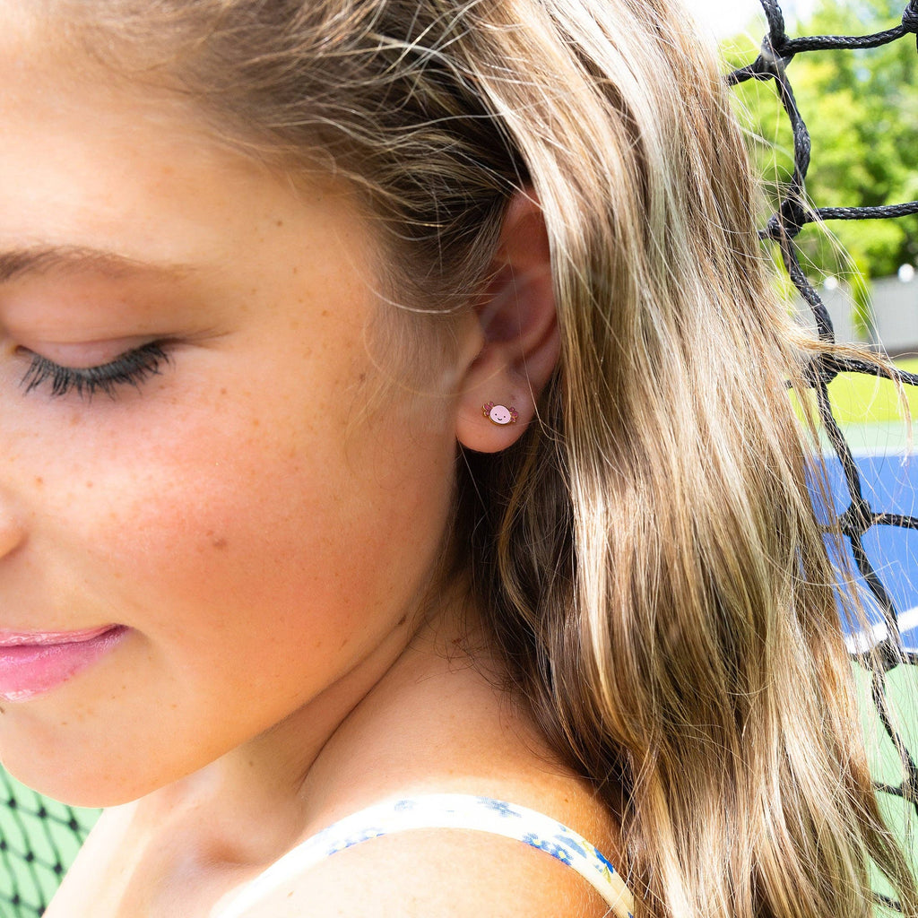 Close-up of a young girl wearing a small earring outdoors.