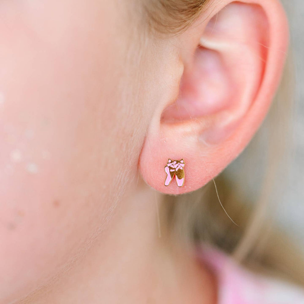 Close-up of an ear wearing a small pink bear-shaped earring.