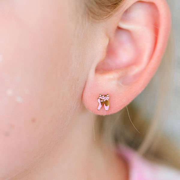 Close-up of an ear wearing a small pink bear-shaped earring.