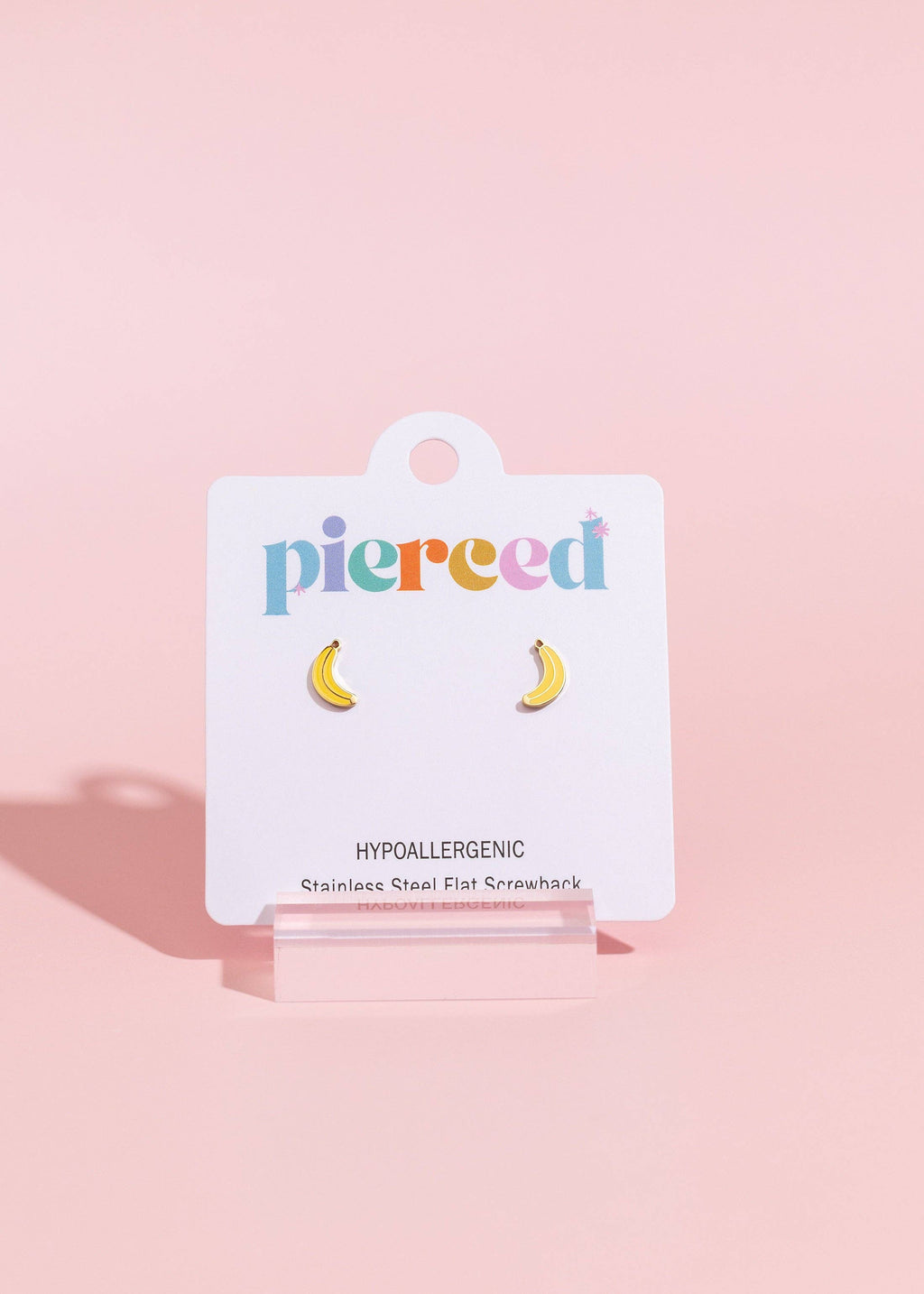 Earring card with banana-shaped earrings on a pink background