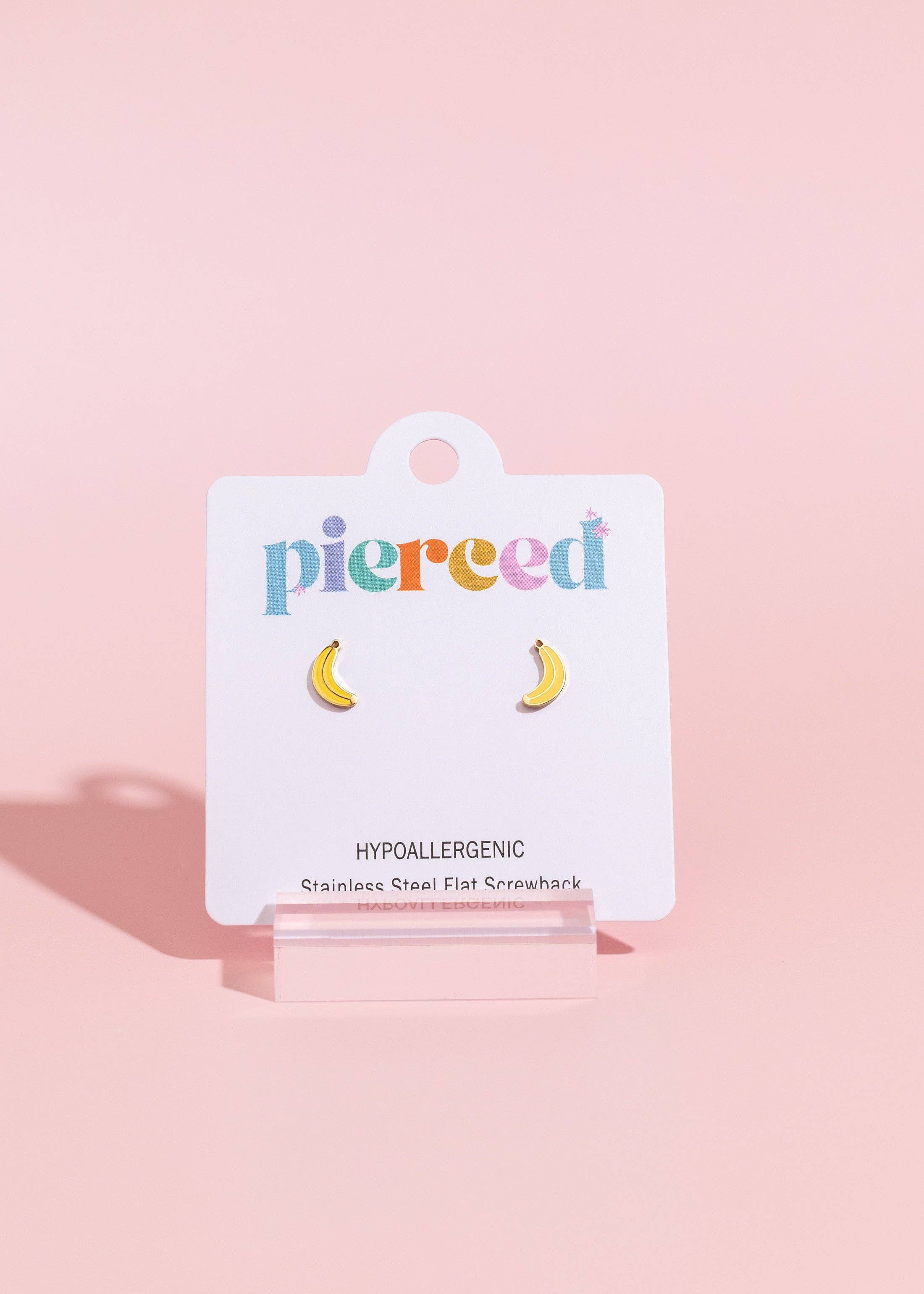 Earring card with banana-shaped earrings on a pink background