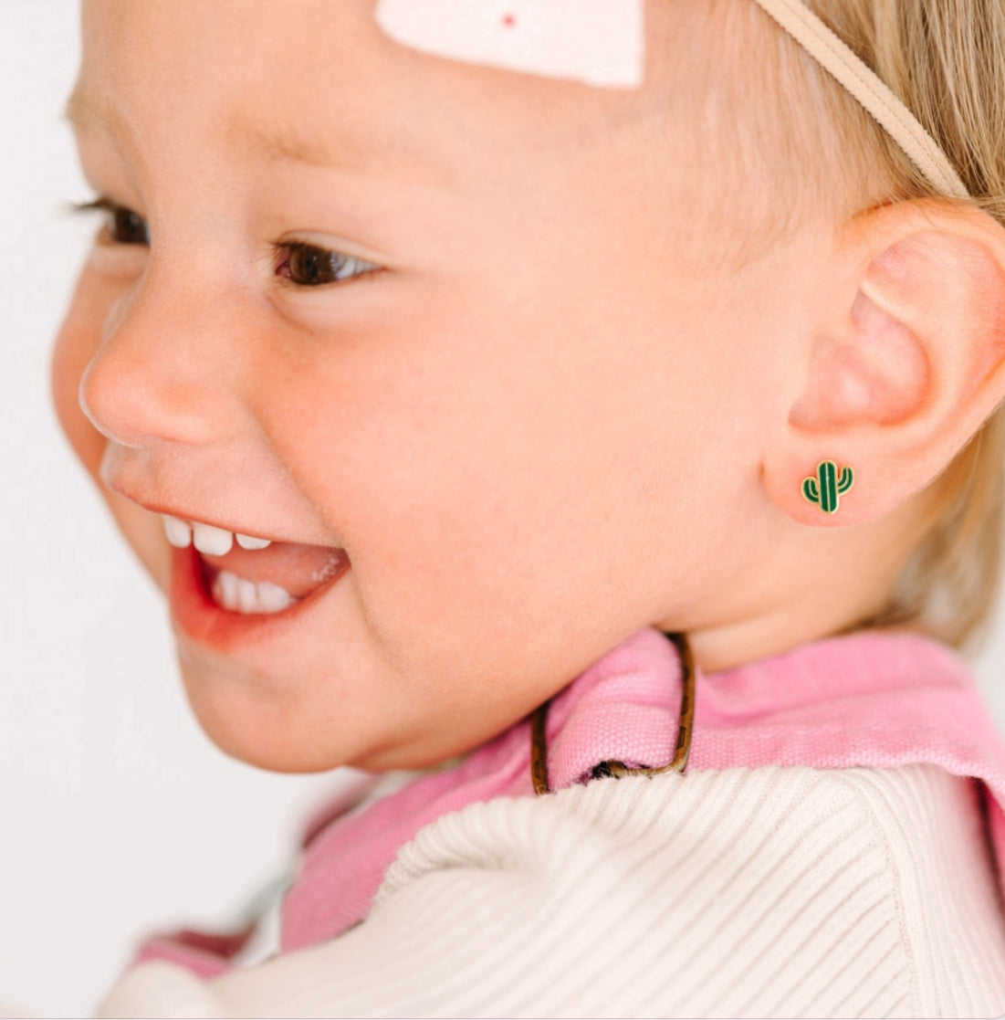 Close-up of a child wearing small green cactus earrings.