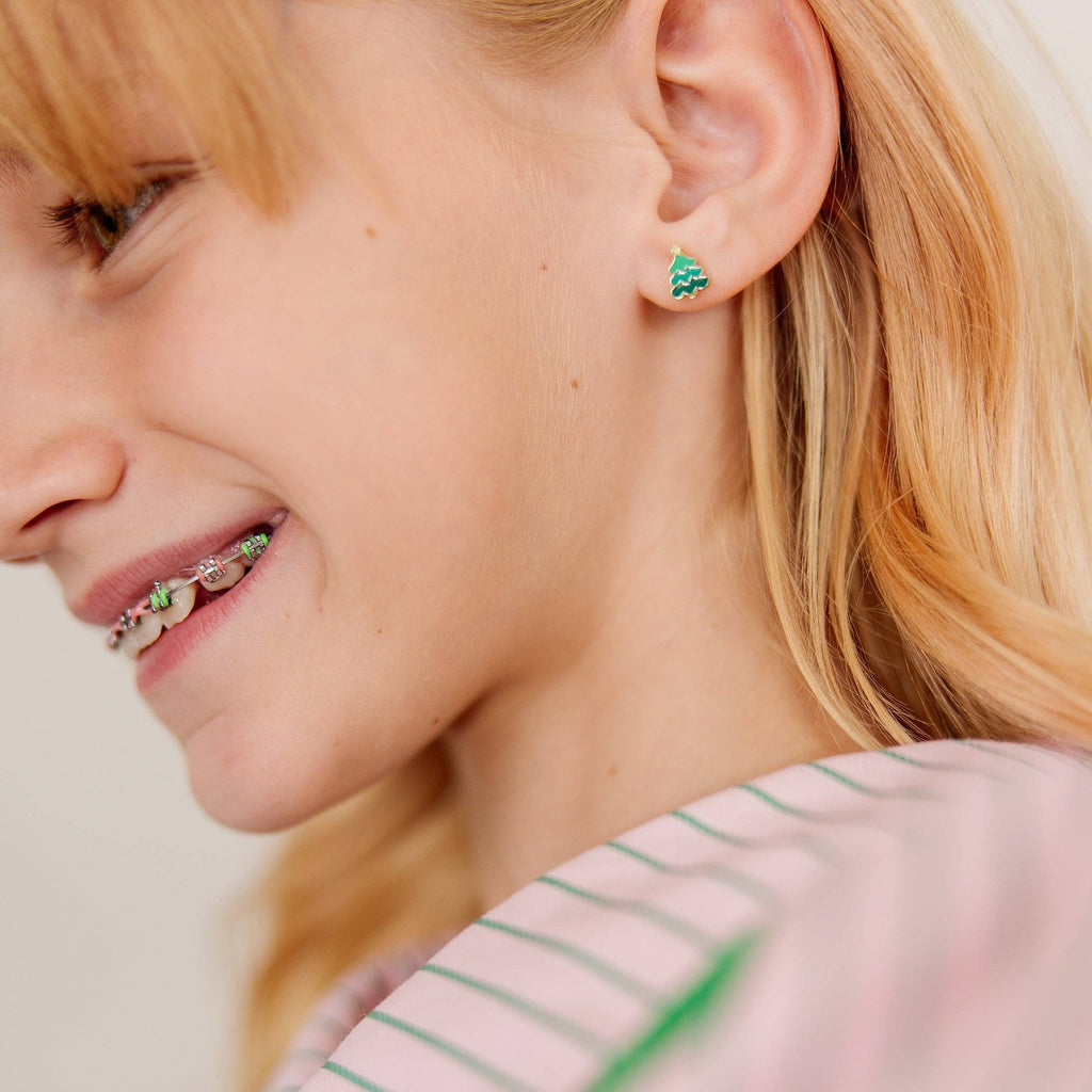 A close-up lifestyle shot of a young woman with blonde hair wearing a small green and gold textured stud earring.