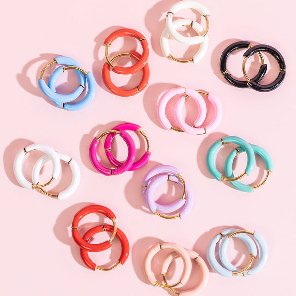 Colorful circular earrings on a pink background
