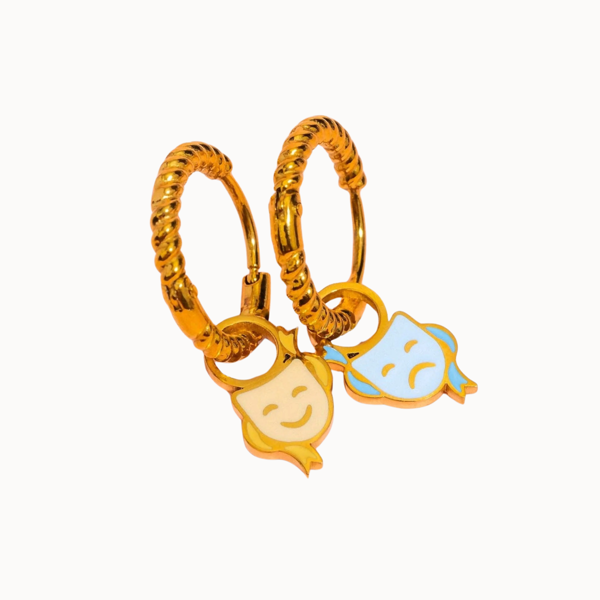 A pair of gold huggie hoop earrings with dangling enamel character charms, one in yellow and one in light blue, on a plain white background.