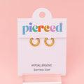 A pair of gold hoop earrings displayed on a white Pierced brand card against a soft pink background.