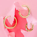 Gold hoop earrings on a pink floral background