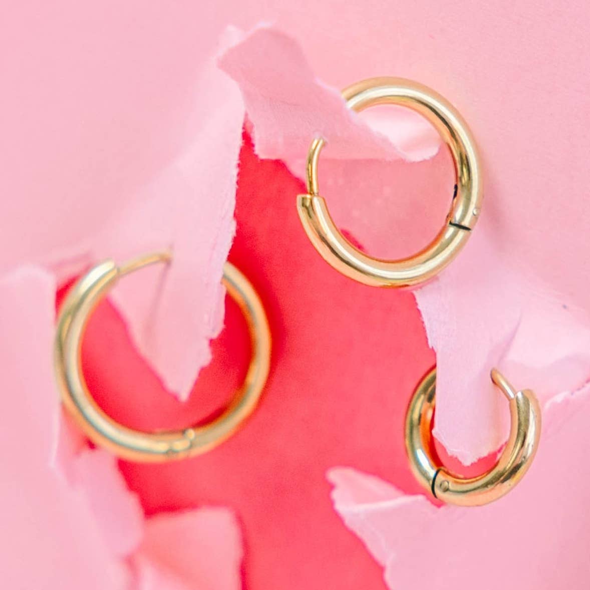 Gold hoop earrings on a pink floral background