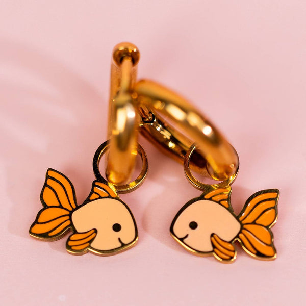 Goldfish-shaped keychains on a gold keyring against a pink background