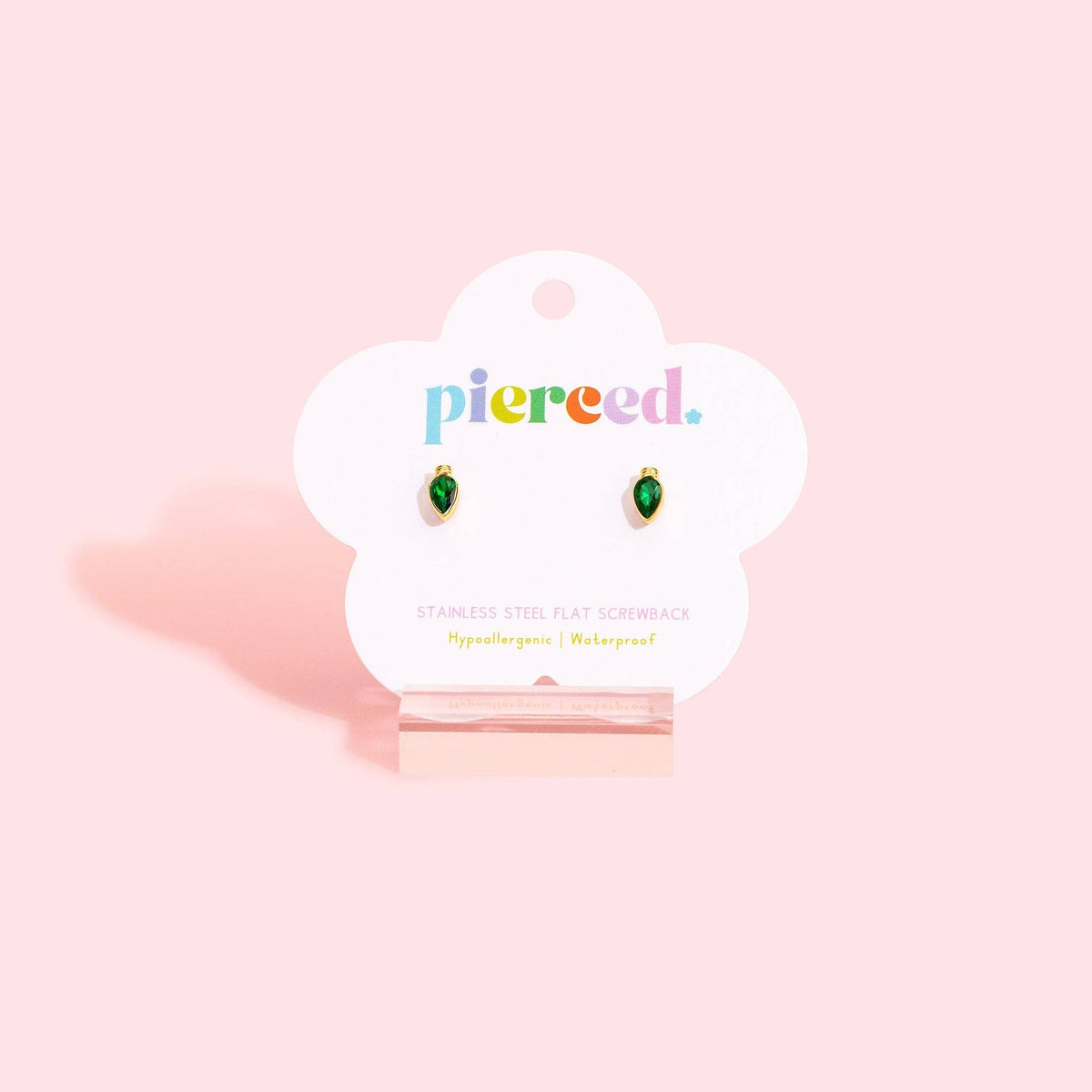 A pair of small green teardrop-shaped screenear earrings displayed on a white cloud-shaped card labeled 'pierced.' against a soft pink background.