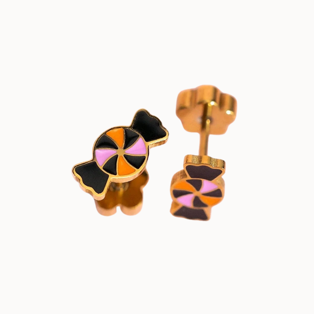A pair of gold stud earrings shaped like a candy and a bear, featuring black, orange, and pink enamel details, shown on a plain white background.