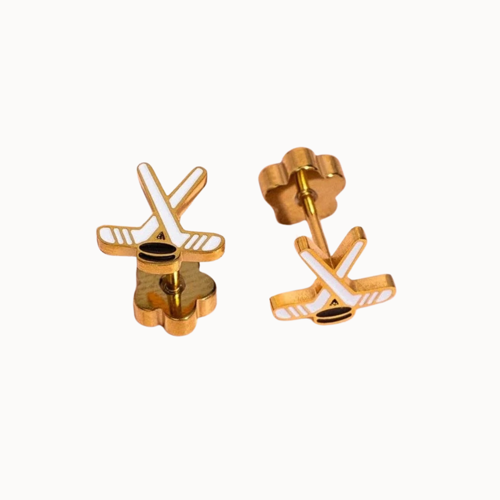 A pair of gold-toned stud earrings shaped like stylized hockey sticks with white accents, shown on a plain light background.