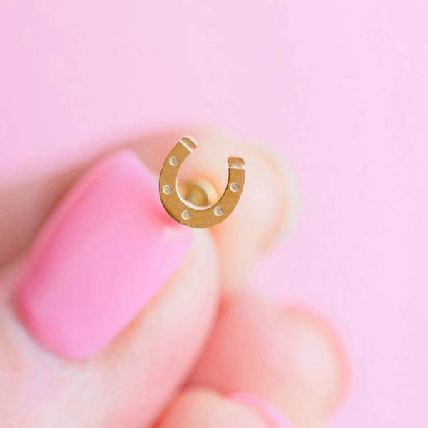 Gold horseshoe charm on a pink background