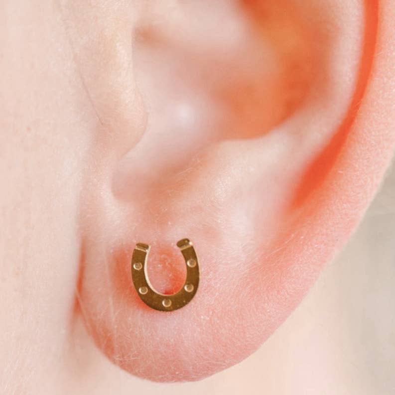 Gold horseshoe-shaped earring on a person's ear