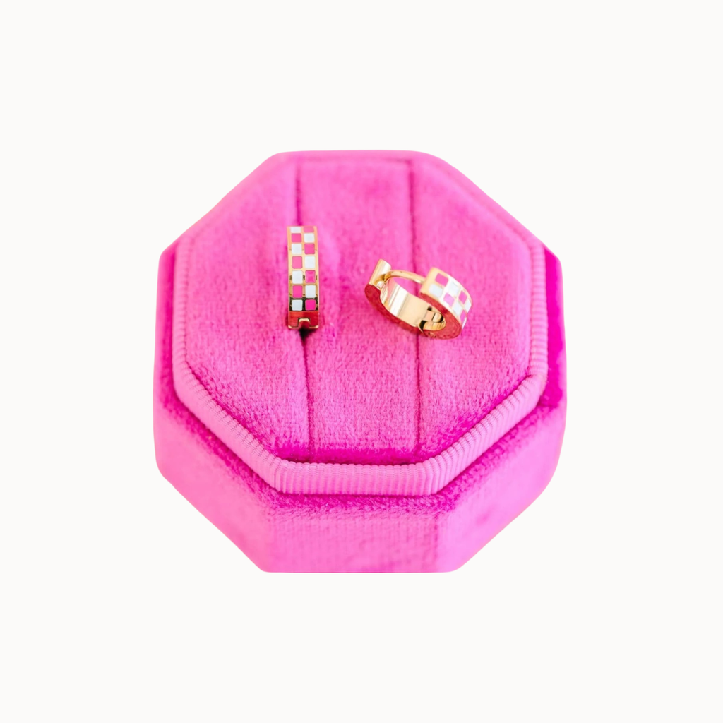 Two small rings displayed on a bright pink octagonal velvet ring box against a plain white background.