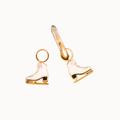 A pair of gold-tone ice skate charms with white enamel detailing against a white background.