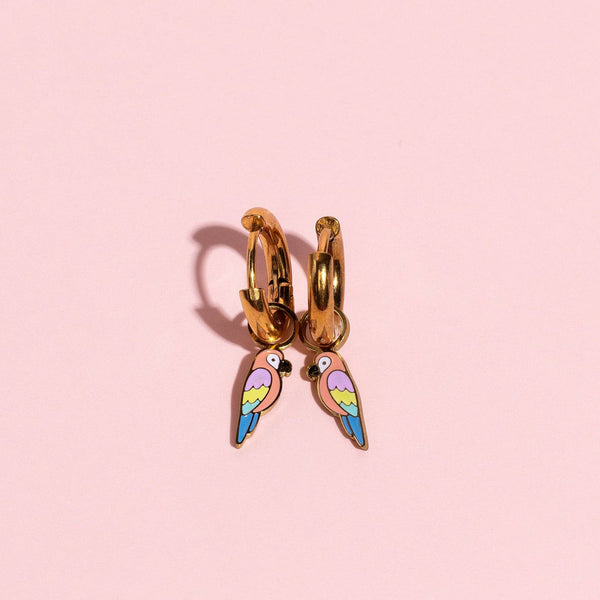 Gold hoop earring with colorful wing design on a pink background