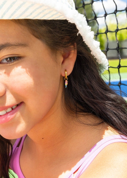 Close-up of a young girl wearing colorful earrings with a tennis court in the background