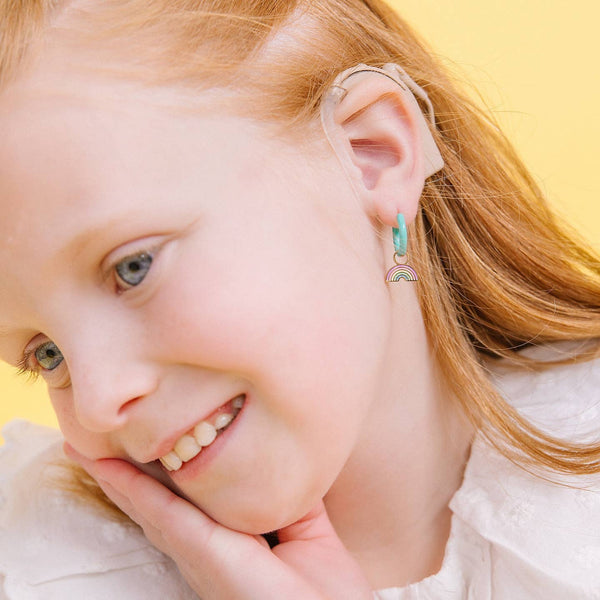 Close-up of a young girl wearing a hearing aid with a yellow background