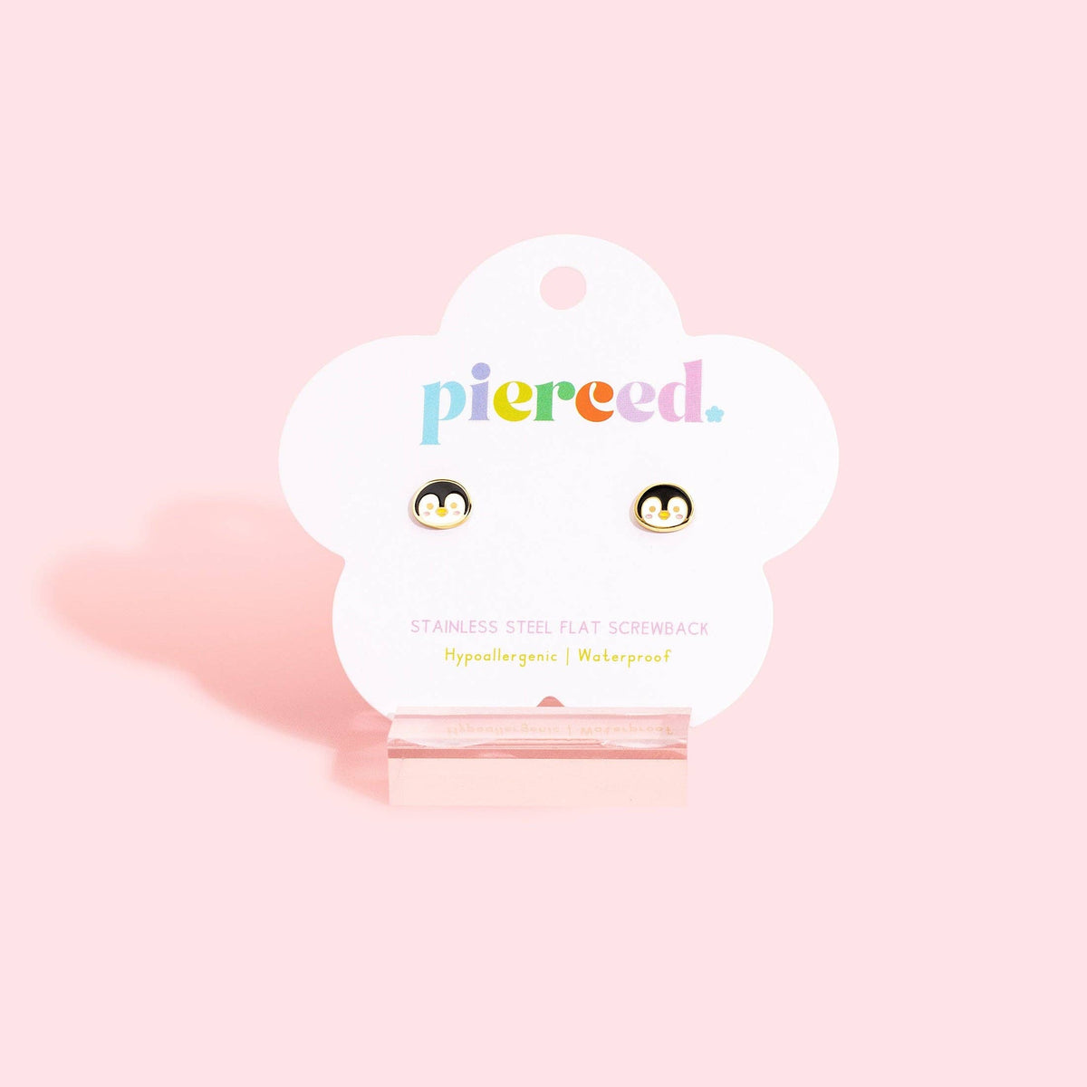 A pair of small flat screwback stud earrings displayed on a white cloud-shaped card that reads 'pierced.' against a soft pink background.