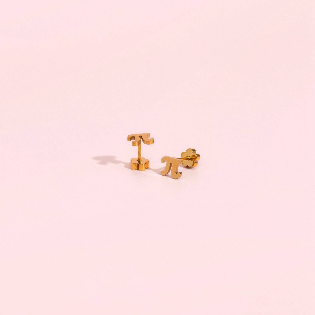 A pair of small gold stud earrings shaped like a stylized letter T and a stylized letter P, displayed on a solid pale pink background.