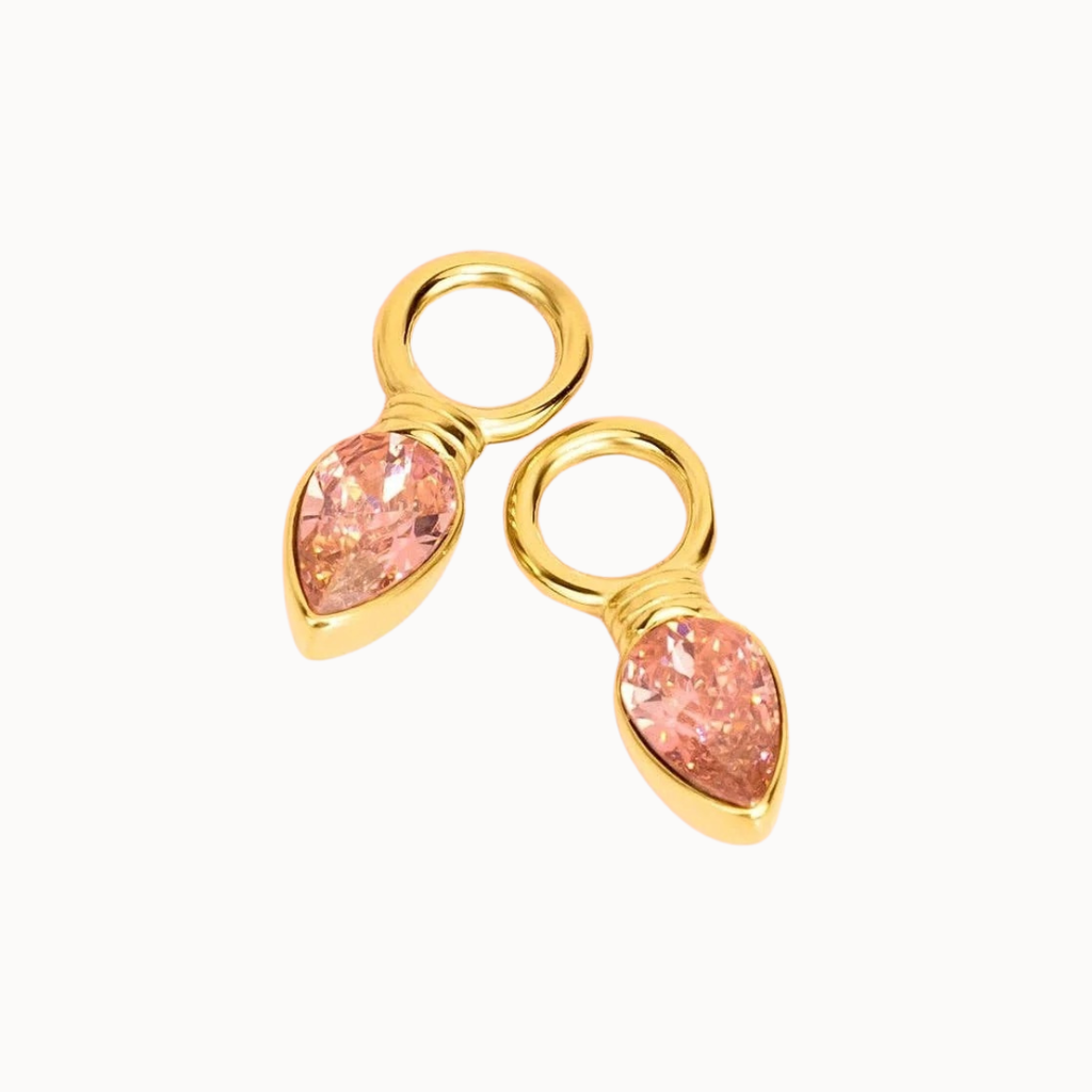 A pair of gold-plated jewelry charms featuring teardrop-shaped pink gemstones in bezel settings with attached circular loops, shown on a plain white background.