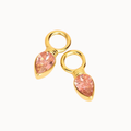 A pair of gold-plated jewelry charms featuring teardrop-shaped pink gemstones in bezel settings with attached circular loops, shown on a plain white background.