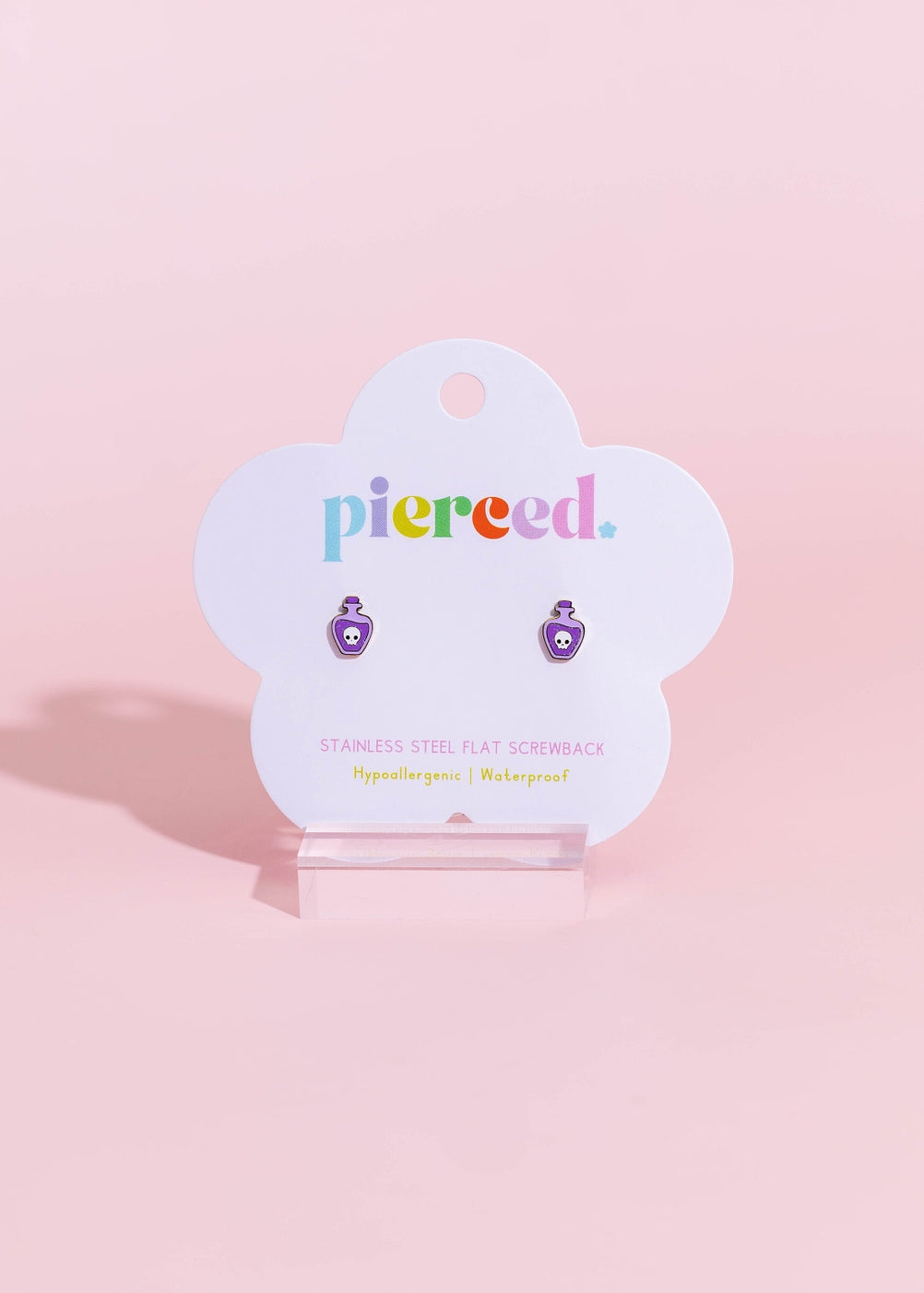A pair of purple and white enamel flat back stud earrings displayed on a white cloud-shaped Piered. brand card, set against a solid pastel pink background.