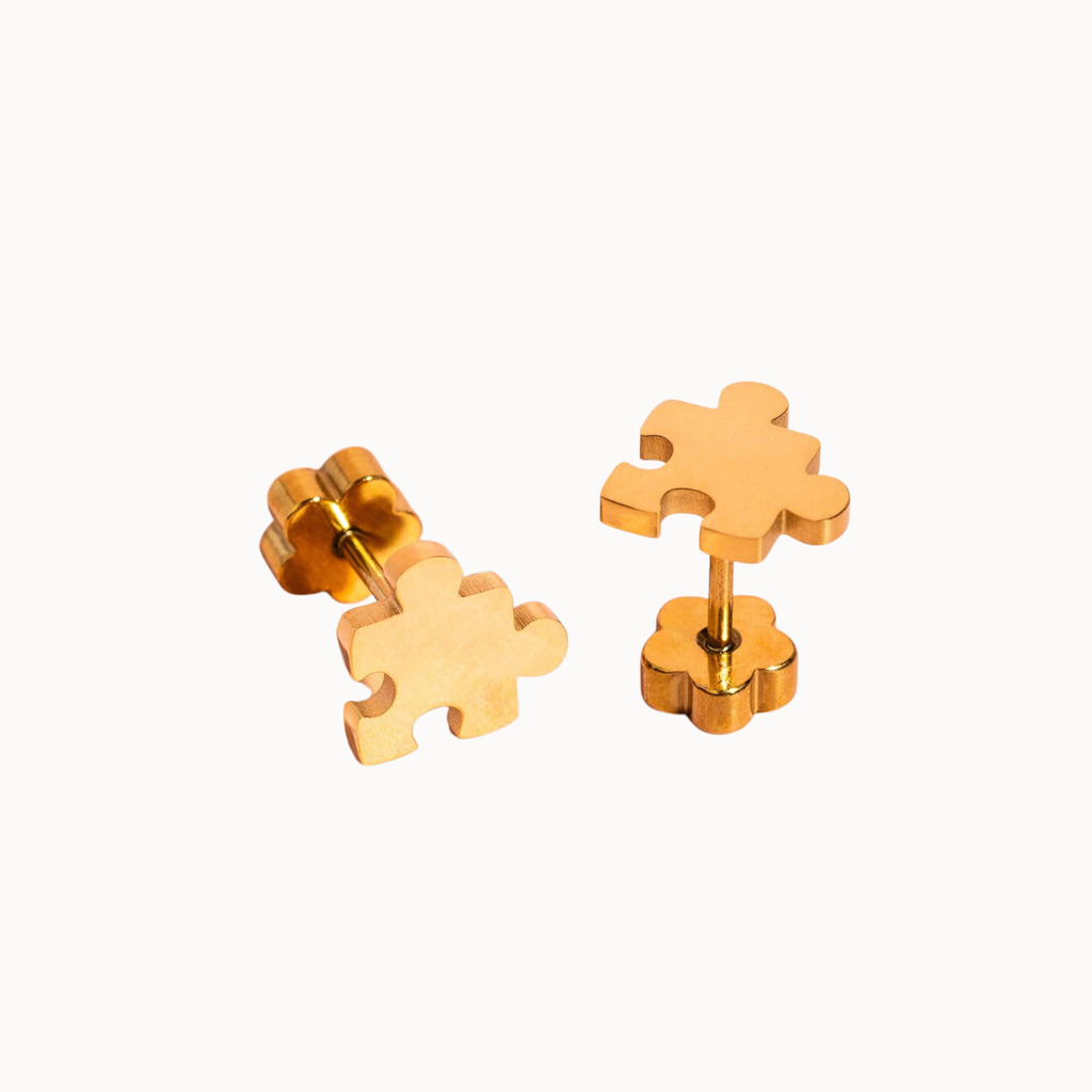 A pair of gold puzzle-piece stud earrings shown from both front and side angles on a clean white background.
