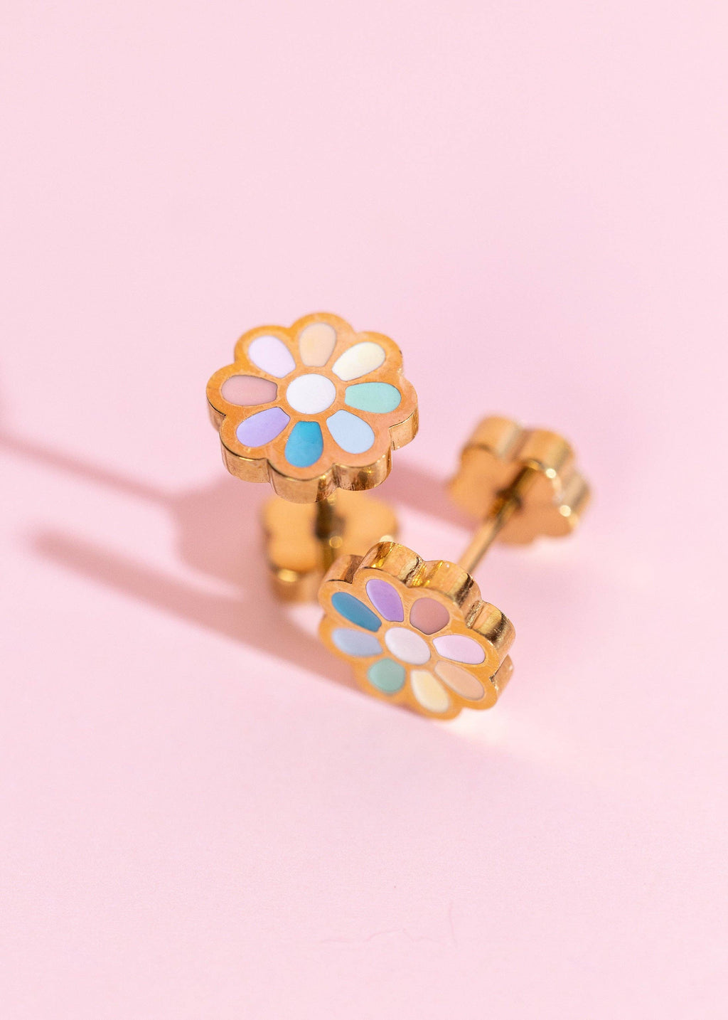 Colorful flower-shaped earrings on a pink background