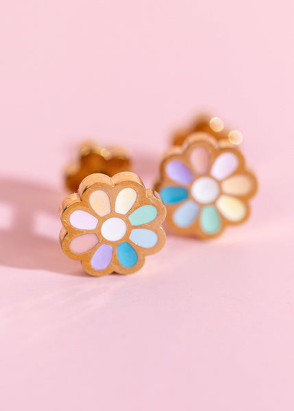 Colorful flower-shaped earrings on a pink background