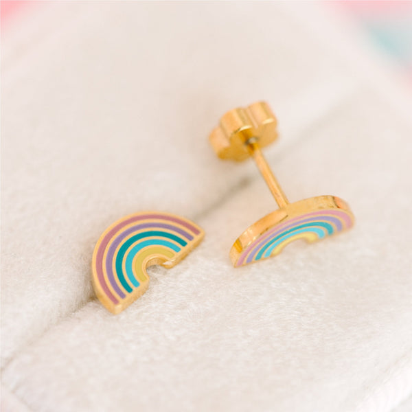 Rainbow-shaped earrings on a soft fabric background