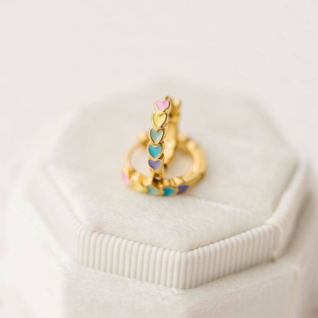 Gold ring with colorful heart-shaped stones on a white surface
